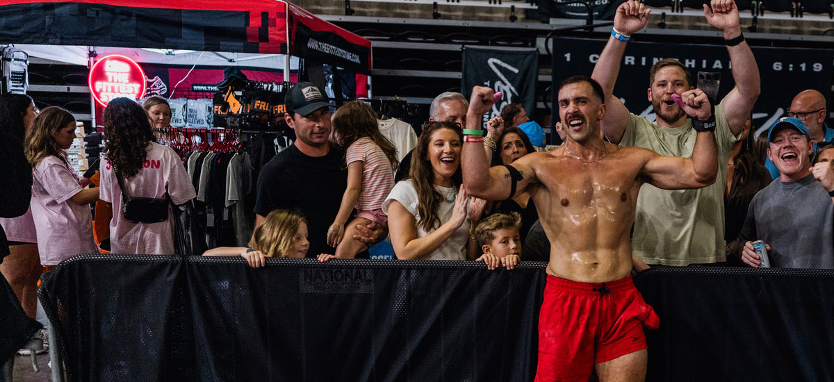 A Magic City Games athlete raises both fists in celebration at the barrier as the crowd cheers behind him.